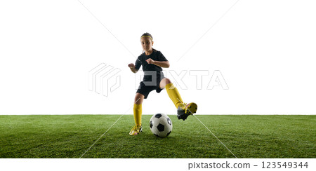 Girl, child in black uniform and yellow sock in motion on field dribbling, learning to control ball against white studio background Girl, child in black uniform and yellow sock in motion on field dribbling, learning to control ball against white studio background 123549344
