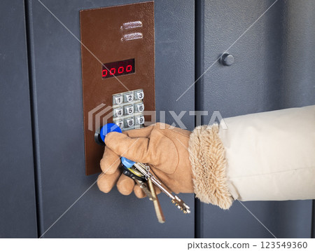 Woman in a warm cloth and gloves opening the electronic lock with the chip on the key chain 123549360