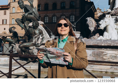 Young female traveler standing with paper map near famous Neptune fountain in Florence. Traveling Europe in summer. Attractive female is exploring new city. Top tourist attraction. High quality photo 123550068