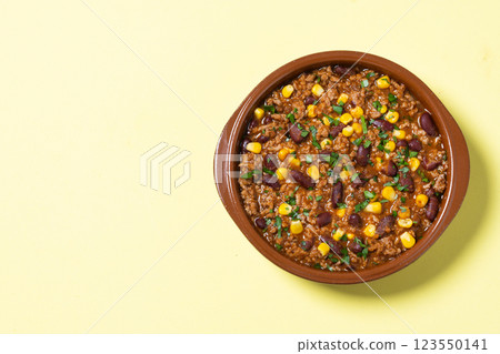 Traditional Mexican Chili con carne. Minced meat and vegetables stew in tomato sauce on yellow background 123550141