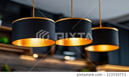 Black pendant lamps enhance the sleek design of a kitchen, casting soft shadows and creating a warm ambiance with natural light 123550733