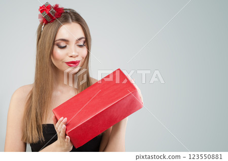 Cheerful young happy woman holding gift present box on grey studio wall background Cheerful young happy woman holding gift present box on grey studio wall background 123550881