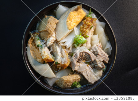 Rolled rice noodles in five-spices broth ingredients are boiled eggs, crispy pork, pork and tofu in brown stewed soup in bowl. 123551093