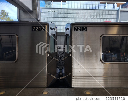 steel brown shiny subway train cars standing at ground station without people against background of city buildings behind fence, open subway platform with standing train on track 123551310