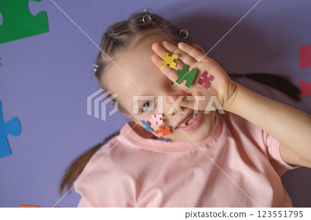 A pretty girl shows a palm with pieces of multicolored paper jigsaw puzzles as a sign of support for Kids with autism spectrum disorder. Education and child development A pretty girl shows a palm with pieces of multicolored paper jigsaw puzzles as a sign of support for Kids with autism spectrum disorder. Education and child development 123551795
