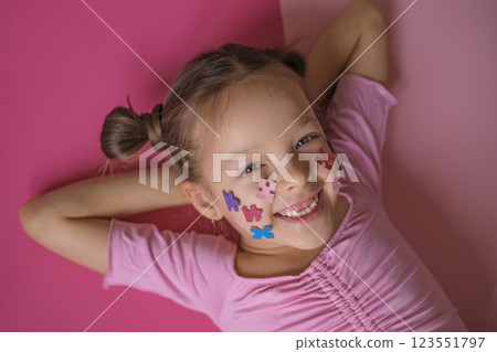 A pretty laughing girl has prepared face decorations for the World Autism Awareness Day as a sign of support for people with the syndrome. 123551797