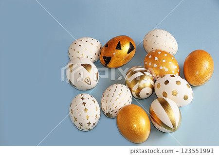 Golden easter eggs on a blue background. Minimal holiday concept. Happy easter background. Creative painting of eggs at home. Golden easter eggs on a blue background. Minimal holiday concept. Happy easter background. Creative painting of eggs at home. 123551991