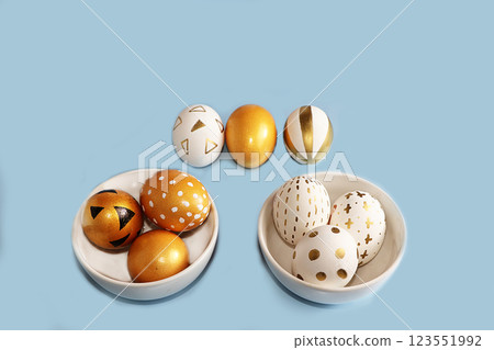 Golden easter eggs on a blue background. Minimal holiday concept. Happy easter background. Creative painting of eggs at home. Golden easter eggs on a blue background. Minimal holiday concept. Happy easter background. Creative painting of eggs at home. 123551992