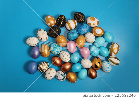 Decorated golden and blue easter eggs on a turquoise background. Minimal holiday concept. Happy easter background. Creative painting of eggs at home, the idea of simple drawings for coloring, a place 123552246