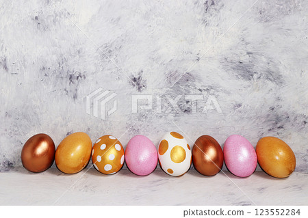 Decorated golden easter eggs on concrete background. Minimal holiday concept. Happy easter background. Creative painting of eggs at home, the idea of simple drawings for coloring, a place for text, a Decorated golden easter eggs on concrete background. Minimal holiday concept. Happy easter background. Creative painting of eggs at home, the idea of simple drawings for coloring, a place for text, a 123552284