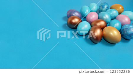 Decorated golden and blue easter eggs on a blue background. Minimal holiday concept. Happy easter background. Creative painting of eggs, place for text, postcard, banner for the screen. 123552286