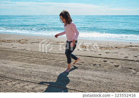 Smiling Child Enjoying at a Sandy Beach on a Sunny Day by the Sea 123552416