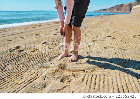 Young Person Enjoying Barefoot Walk on a Pristine Beach Under Clear Blue Skies Young Person Enjoying Barefoot Walk on a Pristine Beach Under Clear Blue Skies 123552423