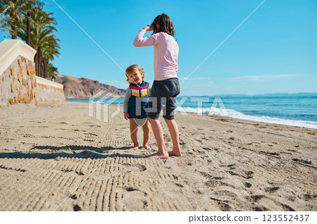 Two Children Playing on a Picturesque Beach Under a Clear Blue Sky Two Children Playing on a Picturesque Beach Under a Clear Blue Sky 123552437