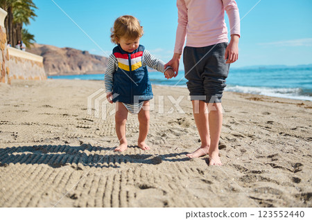 Young Child Exploring a Sandy Beach Holding Hands During a Sunny Summer Day Young Child Exploring a Sandy Beach Holding Hands During a Sunny Summer Day 123552440
