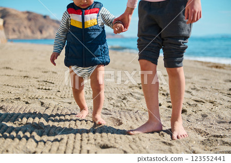Child Holding Hands Walking on Sandy Beach in Summer Daytime 123552441