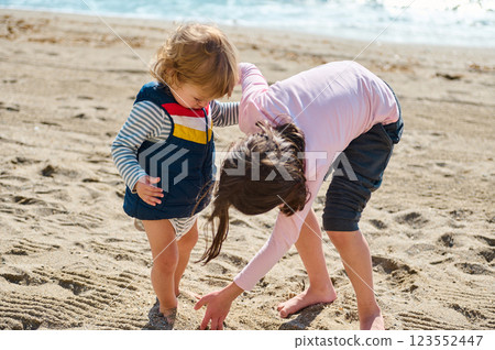 Two Children Playing Together on a Sunny Beach, Creating Memories in the Sand Two Children Playing Together on a Sunny Beach, Creating Memories in the Sand 123552447