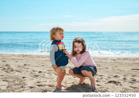 Children Playing Together on a Sandy Beach by the Ocean on a Sunny Day Children Playing Together on a Sandy Beach by the Ocean on a Sunny Day 123552450