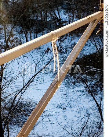 Long icicles hanging from the pipe and glowing in the rays of the golden setting sun 123552676