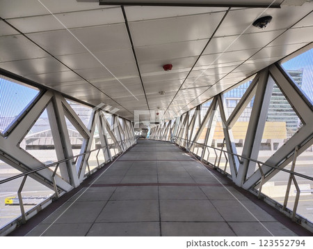 overpass with geometric structure made of white metal and through holes between abstractly arranged beams, a fragment of a corridor above a road for safe movement overpass with geometric structure made of white metal and through holes between abstractly arranged beams, a fragment of a corridor above a road for safe movement 123552794
