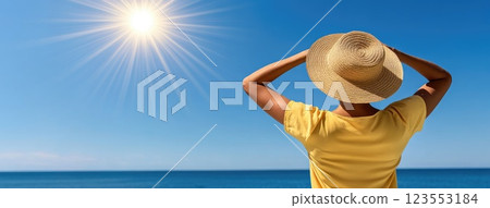 Sunlit straw hat rests against a backdrop of sparkling blue water, evoking the essence of summer relaxation and warmth 123553184