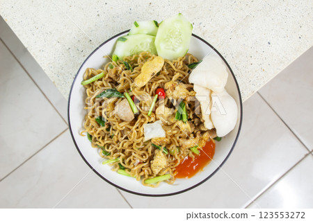 top view of fried noodles topped with shredded chicken, meatballs, fried egg on a plate at the corner of a marble table top view of fried noodles topped with shredded chicken, meatballs, fried egg on a plate at the corner of a marble table 123553272