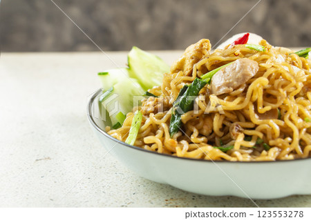 closeup of fried noodles filled with meatballs, fried egg, cucumber and vegetables on white marble table texture, negative space closeup of fried noodles filled with meatballs, fried egg, cucumber and vegetables on white marble table texture, negative space 123553278