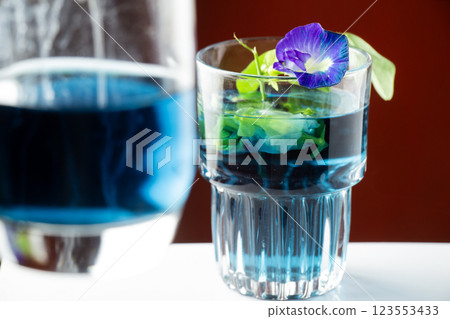 Purple flower tea or butterfly pea flower isolated with focus on a glass on an orange background Purple flower tea or butterfly pea flower isolated with focus on a glass on an orange background 123553433