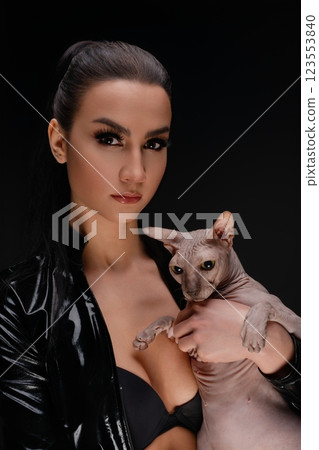 Beauty and elegance of a woman holding a sphynx cat in a dark setting 123553840