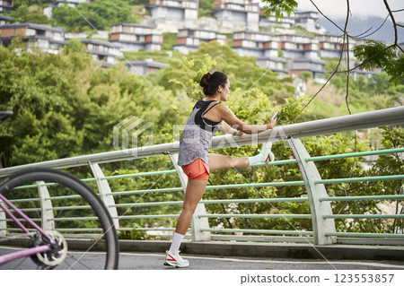 young asian woman pressing legs before exercising outdoors young asian woman pressing legs before exercising outdoors 123553857