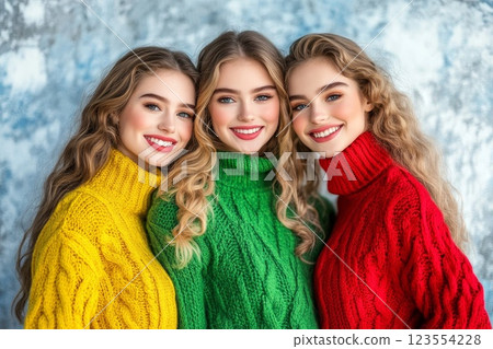 three girls in green, yellow and red sweaters on a light background 123554228