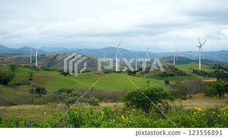 Wind turbines on a hillside generate clean energy against a cloudy sky. 123556891