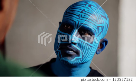 Man with blue body paint listening to someone 123557182