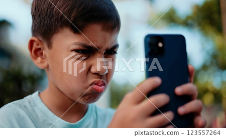 Young boy making funny faces while using smartphone Young boy making funny faces while using smartphone 123557264
