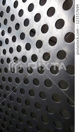 Stainless Steel Mesh Displays Intricate Pattern of Perforations and Reflections in Bright Light 123557694