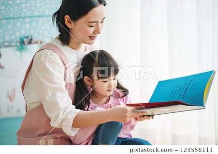 A nursery teacher reading a picture book to children 123558111