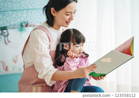 A nursery teacher reading a picture book to children 123558112