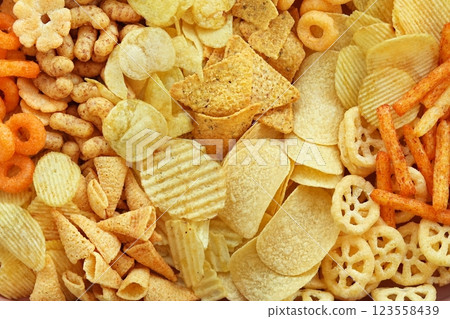 Colorful mix of salty snacks for beer varieties: chips and pretzels, onion rings and crackers. Non-healthy junk food background Colorful mix of salty snacks for beer varieties: chips and pretzels, onion rings and crackers. Non-healthy junk food background 123558439