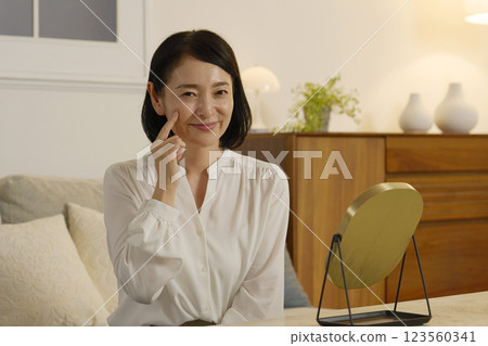 A woman in her 50s touching her cheek with her index finger A woman in her 50s touching her cheek with her index finger 123560341