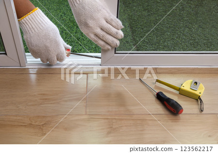 Worker adjust roller of aluminium sliding window. 123562217