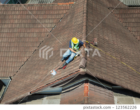 Worker man repairing eaves and tile of the old roof. 123562226