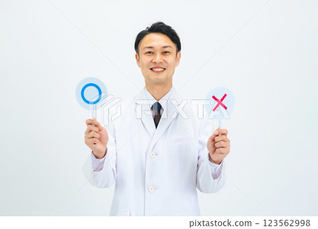 A middle-aged male doctor, scientist, or researcher in a white coat showing a circle mark and a cross mark 123562998