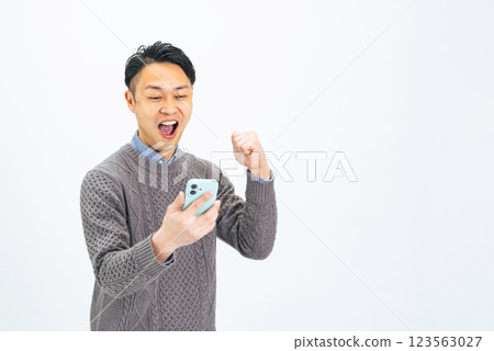 A middle-aged man doing a fist pump while looking at his smartphone 123563027