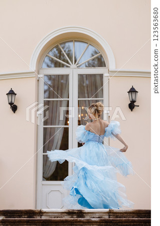 Elegant Woman in a Flowing Blue Gown Walking Down the old stone Stairs 123563680