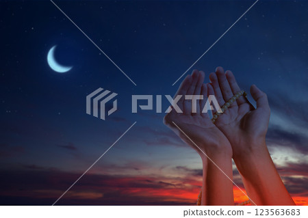 Muslim man praying with prayer beads and a crescent moon in the night scene background. Concept of Religion, Spiritual or Ramadan 123563683
