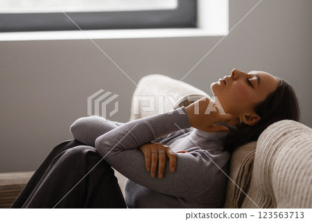 A woman is sitting on a couch with her legs crossed A woman is sitting on a couch with her legs crossed 123563713