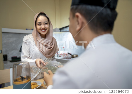 Asian Muslim wife preparing food for her family. Concept of Eid Al Fitr, Idul Fitri, and Ramadan Mubarak celebration Asian Muslim wife preparing food for her family. Concept of Eid Al Fitr, Idul Fitri, and Ramadan Mubarak celebration 123564073