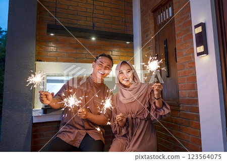 Asian Muslim couple playing fireworks at hometown. Concept of Eid Al Fitr, Idul Fitri, Lebaran, and Ramadan Mubarak celebration 123564075