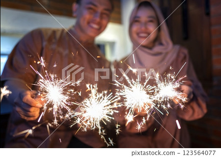 Asian Muslim couple playing fireworks at hometown. Concept of Eid Al Fitr, Idul Fitri, Lebaran, and Ramadan Mubarak celebration Asian Muslim couple playing fireworks at hometown. Concept of Eid Al Fitr, Idul Fitri, Lebaran, and Ramadan Mubarak celebration 123564077