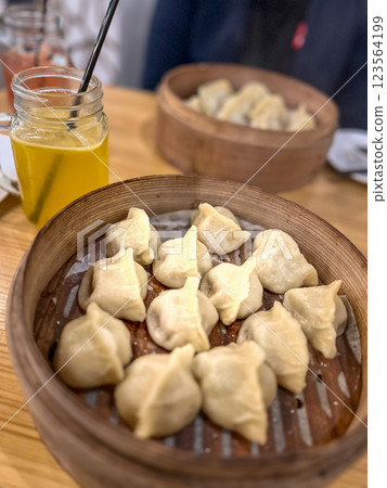 Steamed dumplings in in wooden bamboo steamer like a plate with a glass of juice 123564199